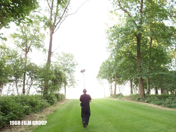 Image of a man walking with a video mike.