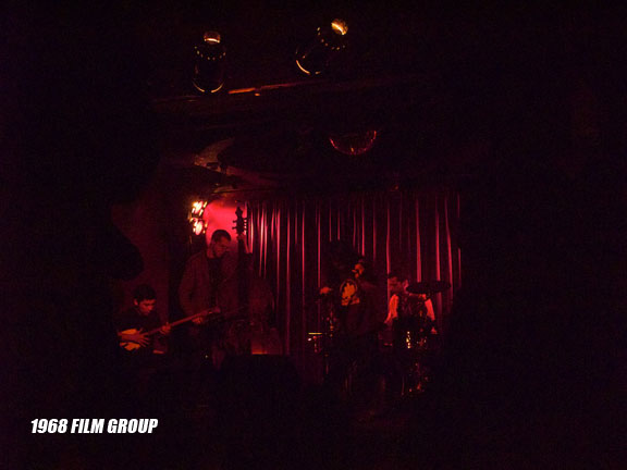 Image of a band playing on a dimly lit stage.